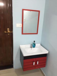 a bathroom with a red and white sink and a mirror at River Heart Homestay in Aranmūla
