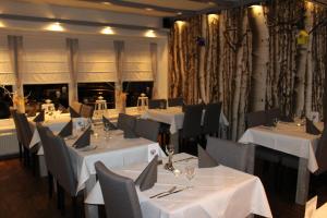 a dining room with white tables and chairs and curtains at Hotel Restaurant Jägerhof in Braunschweig