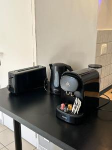 un tavolo nero con una macchinetta del caffè di L'Adrien Hébrard parking facile a Grisolles Altre 2 foto