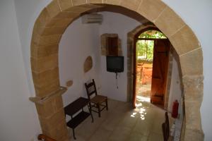 een boog die leidt naar een woonkamer met een televisie bij Patriko Traditional Stone Houses in Vafés