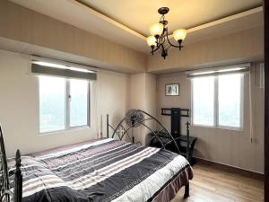 セブシティにある2-BR condo unit in IT Parkのベッドルーム1室(シャンデリア付きのベッド1台、窓2つ付) +30枚の写真