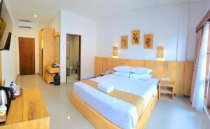 a bedroom with a large bed with white sheets and pillows at Satriya Cottages in Kuta