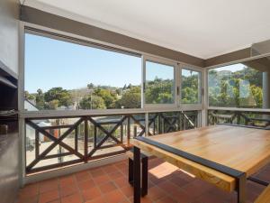 a balcony with a wooden table and large windows at Summer Place in Knysna