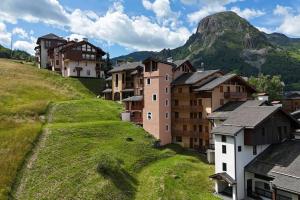 a village on a hill with a mountain in the background at Le Neiger - Appartement Emeraude in Saint-Martin-de-Belleville