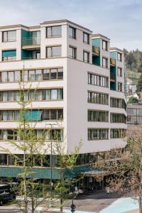 a tall white building with trees in front of it at The Yarn in Horgen