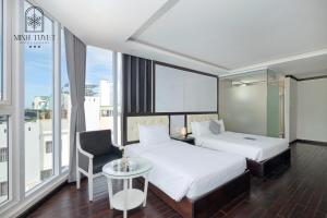 a hotel room with two beds and a chair at Minh Tuyết Luxury Hotel in Nha Trang +28 photos