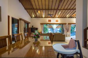 Una sala de estar con un sofá, una mesa y sillas. en ViLLA GREEN MANGGO III, en Seminyak