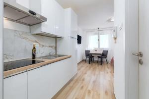a kitchen with white cabinets and a table with chairs at Skyline Apartment in Veruda