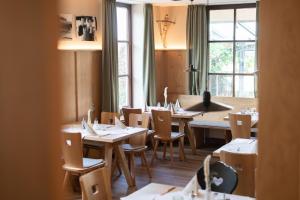 ein Esszimmer mit Tischen und Stühlen und einem Fenster in der Unterkunft Hotel Häußler in Langenbruck
