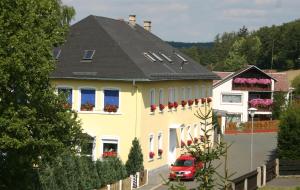 uma casa amarela com um carro vermelho estacionado em frente em Hotel "Alte Schule" Trogen em Trogen