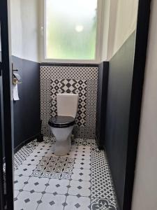 a bathroom with a toilet with a black and white floor at La Demeure Envoutée in Trélon +4 photos