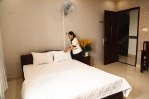 Eine Frau steht neben einem Bett in einem Zimmer in der Unterkunft MK Two Hotel in Mỹ Tho + 45 Fotos