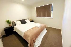 Un dormitorio con una cama con sábanas blancas y una ventana. en Kellyville Spacious Modern House Park&Lake, en Kellyville