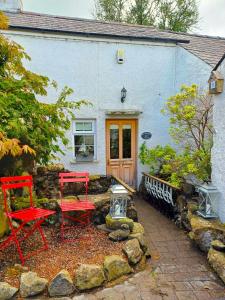 deux chaises rouges assises devant une maison dans l'établissement Riverside Cottage at Logwood Mill, à Ballyclare 37 autres photos