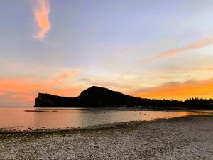 a sunset on a beach with a mountain in the background at AHG Donna Silvia Wellness Hotel in Manerba del Garda