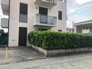 a white building with black doors and a hedge at Monolocale Campo Romano in Schio