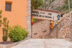 ein Straßenschild an einer Steinmauer mit einer Flagge in der Unterkunft Hotel de La Trucha in Villarluengo