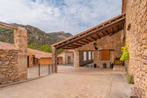 einen Eingang zu einem Steingebäude mit einem Zaun in der Unterkunft Hotel de La Trucha in Villarluengo