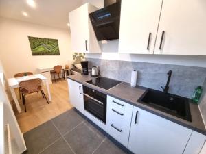 パッサウにあるWohnung Inn - im Zentrum, Küche, Parkplatz, ruhig gelegenの白いキャビネットとシンクとテーブルのあるキッチン
