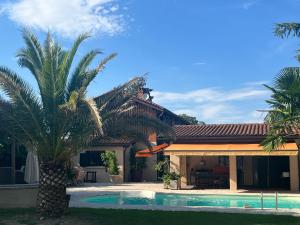 a house with a palm tree next to a swimming pool at Le Moulin in Marlieux