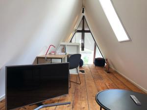 an attic room with a desk and a tv on a wooden floor at Banzai City Amsterdam in Amsterdam