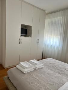 a white bedroom with white cabinets and towels on a bed at Le Piazzette 2 in Schio