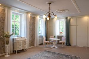 a room with a table and chairs and windows at Schlosshotel Wilhelmsthal in Schäferberg