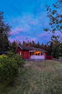 a red house on a field with a yard at FoRest House in Rosenfors