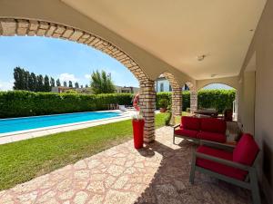 eine Terrasse mit einem roten Sofa und einem Pool in der Unterkunft Villa Marina - Risveglio Vista Lago con Piscina in San Martino della Battaglia