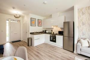 une cuisine avec des armoires blanches et un réfrigérateur en acier inoxydable dans l'établissement Homi Host-Apricot House, à Birmingham