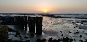 a sunset on a beach with the sun setting at Ferienwohnung Helgoland in Dorum Neufeld +7 photos