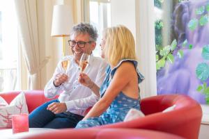 a man and a woman sitting on a couch drinking wine at Wellnesshotel Rothfuß mit Spa und 2 Schwimmbädern in Bad Wildbad