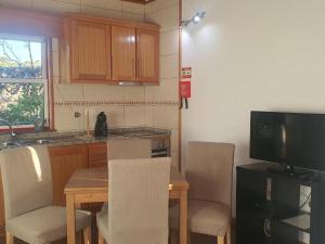 a kitchen with a table with chairs and a television at Casa da estrela sirius in Cabeço Chão