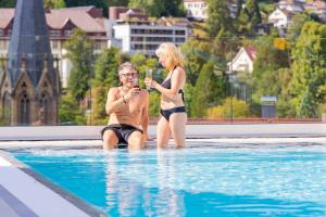 a man and a woman sitting in a swimming pool at Wellnesshotel Rothfuß mit Spa und 2 Schwimmbädern in Bad Wildbad