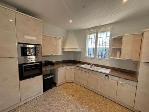 una cocina con armarios blancos y electrodomésticos negros en Villa Centre Mandelieu-la-Napoule, en Mandelieu-la-Napoule