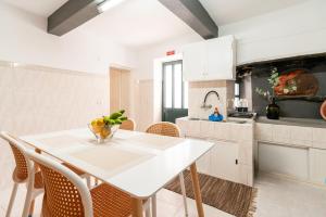 a white kitchen with a white table and chairs at Casa Da Tia in Arco da Calheta
