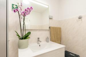 a bathroom with a sink and a vase with purple flowers at Casa Da Tia in Arco da Calheta +9 photos