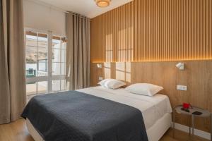 a bedroom with a bed and a large window at Casa da Palmeira by An Island Apart in Porto Santo