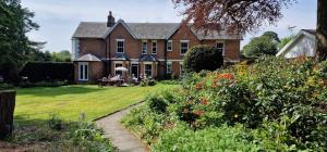a house with people sitting at a table in the yard at Claridge House Retreat Centre Inc Continental Vegetarian or Vegan Breakfast in Lingfield