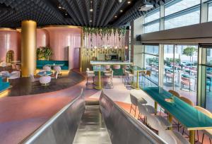 a restaurant with a bar and tables and chairs at Barceló Malaga in Málaga