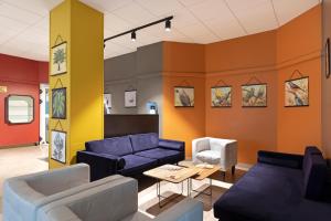 a living room with blue couches and orange walls at B&B Hotel Como City Center in Como