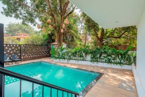 a swimming pool in a backyard with a fence and trees at Studio 109 Apartment by tisyastays in Arpora