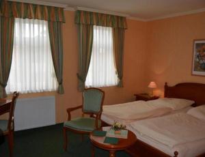 una camera da letto con un letto, una sedia e due finestre di Pension Alter Kutschenbauer a Wernigerode