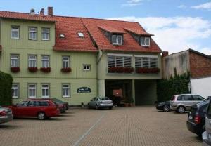 un grande edificio con auto parcheggiate in un parcheggio di Pension Alter Kutschenbauer a Wernigerode