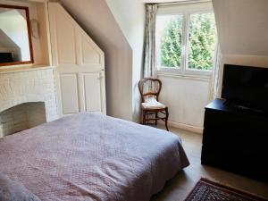 ein Schlafzimmer mit einem Bett, einem TV und einem Stuhl in der Unterkunft Villa Barracuda in Le Touquet-Paris-Plage