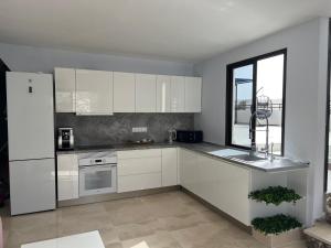 Una cocina con gabinetes blancos y una ventana. en Small room in 4 bedroom penthouse Spectacular patio views, en Puerto de Santiago