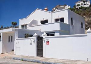 ein weißes Haus mit einem Tor und einem Zaun in der Unterkunft Apartamento,BBQ, cerca del mar in Charco del Pino