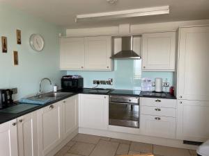 a kitchen with white cabinets and a sink at B2 Waterfoot Apartment in Newcastle