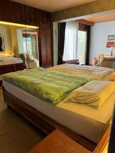 a large bed with a green comforter in a bedroom at Haus mit Pool im Herzen Bochums in Bochum