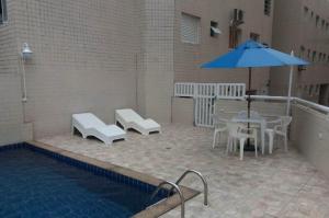 a patio with a table and umbrella next to a pool at Apartamento com piscina! in Samaritá